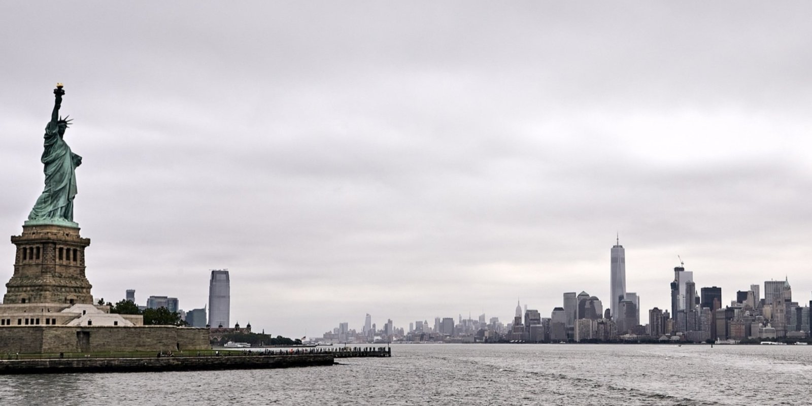 Panorama view of Staten Island beside the choppy Hudson River, with Manhattan’s skyline under overcast gray skies.