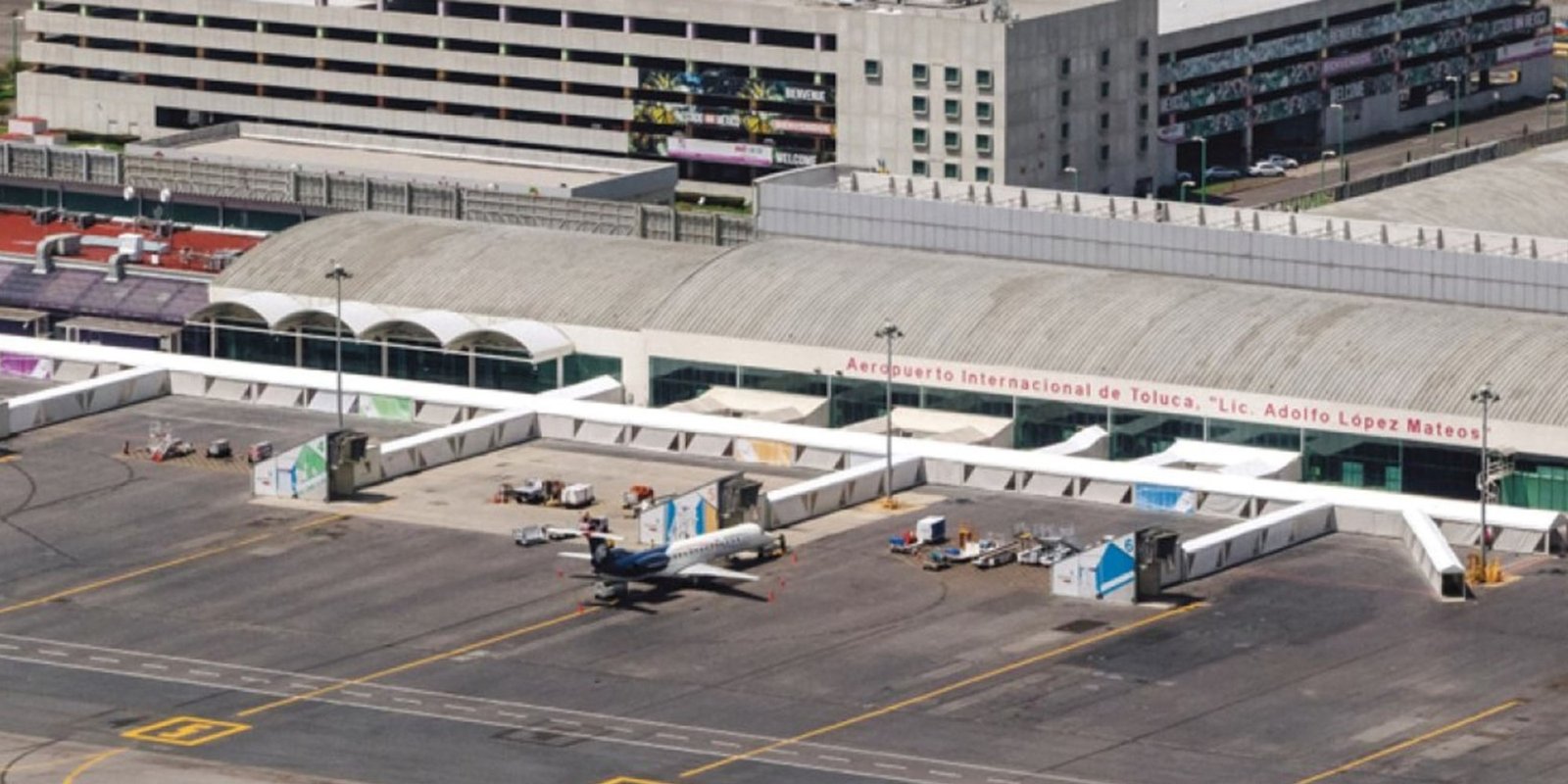 Panorama view of Teterboro airport terminal, with parked aircraft, gates, runway, and green fields.