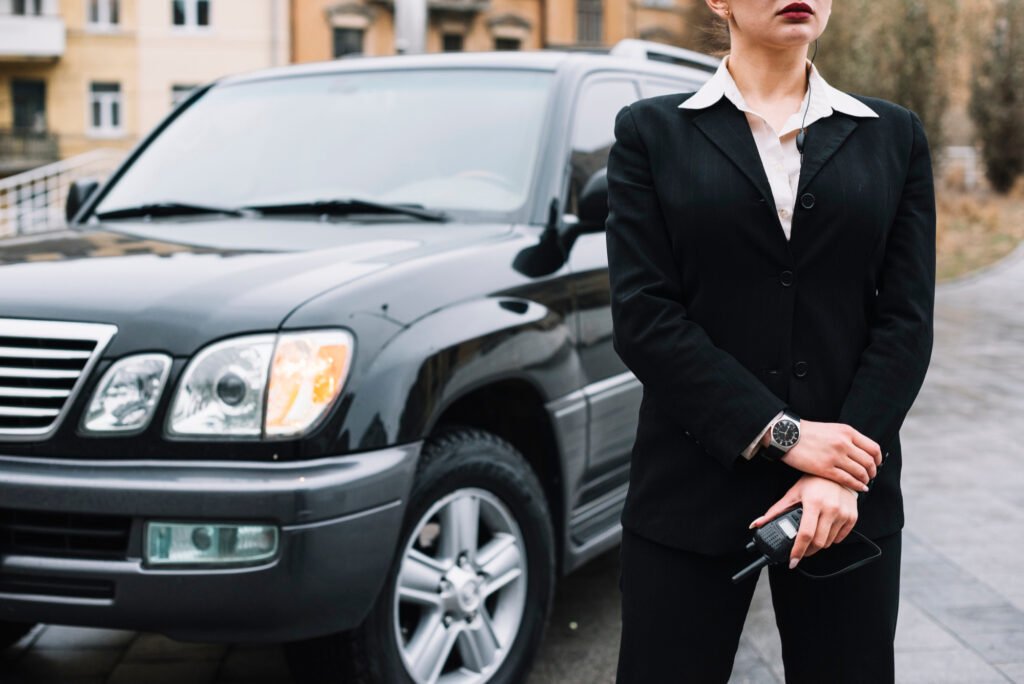 Professional woman in a black suit stands beside a luxury SUV, holding car keys in an urban setting, conveying confidence and executive style.