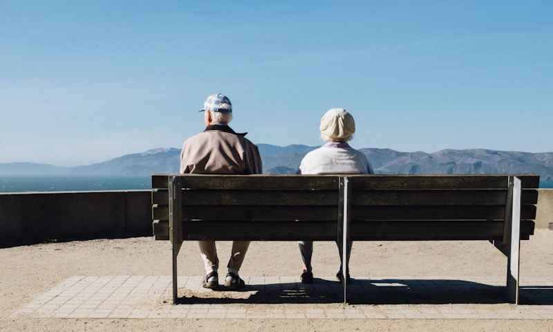 Older couple sitting on a bench looking out at the water